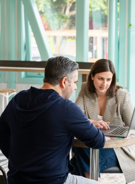 Two people sitting at a desk looking at a computer screen